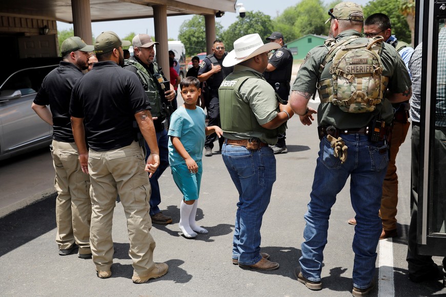 A child gets on a school bus as law enforcement personnel guard the scene of a suspected shooting near Robb Elementary School in Uvalde, Texas, U.S. May 24, 2022.  REUTERS/Marco Bello