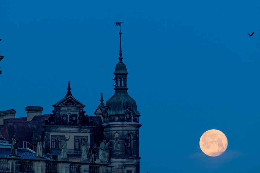 A full moon known as the "Strawberry Moon" sets behind the old town district in Dresden, Germany, June 15, 2022. REUTERS/Matthias Rietschel