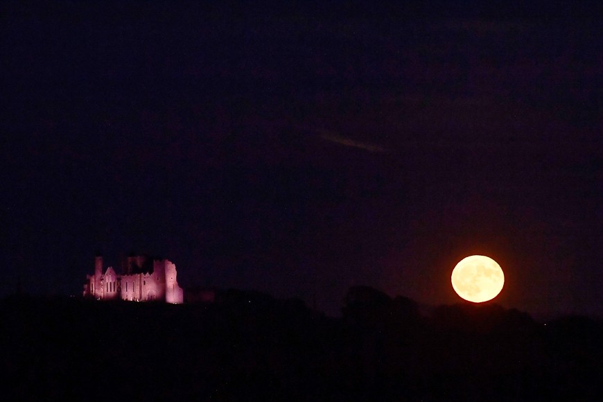 A full moon known as the "Strawberry Moon" rises beside the Rock of Cashel, in Cashel, Ireland, June 14, 2022. Picture taken June 14, 2022. REUTERS/Clodagh Kilcoyne