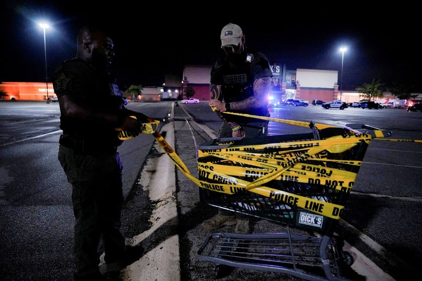 Law enforcement officers attach a crime scene tape to a shopping cart after a shooting at a mall in the Indianapolis suburb of Greenwood, Indiana, U.S. July 17, 2022. REUTERS/Cheney Orr   REFILE - QUALITY REPEAT