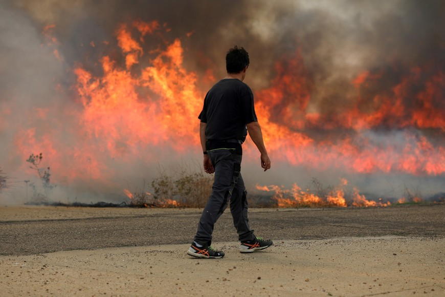 A neighbour watches a fire burning a wheat field between Tabara and Losacio, during the second heatwave of the year, in the province of Zamora, Spain, July 18, 2022. REUTERS/Isabel Infantes