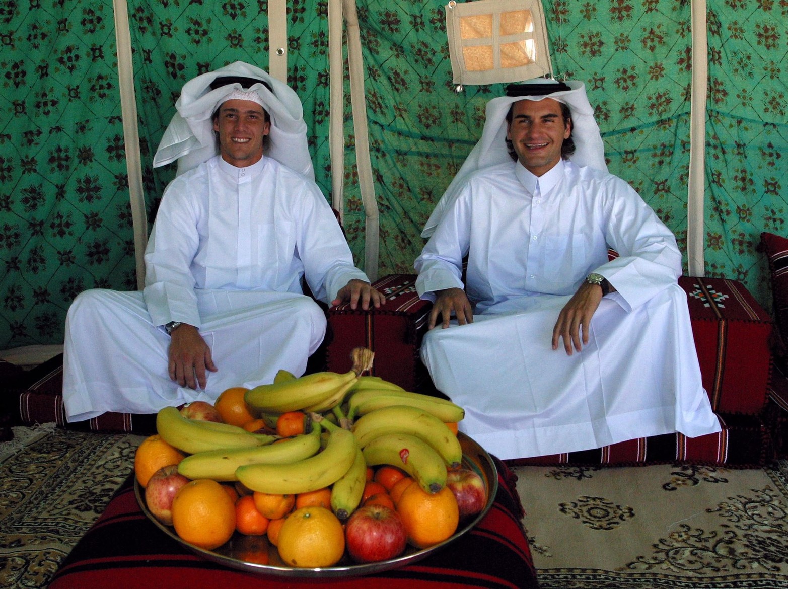 2 de enero de 2005. El número uno del tenis Roger Federer  y el ganador del Abierto de Francia de Argentina, Gaston Gaudio, posan mientras usan un vestido tradicional de Qatar durante un viaje de desierto en las afueras de Doha.  AFP/Karm Jaafar