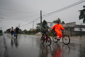 People walk under the rain ahead of the arrival of Hurricane Ian in Coloma, Cuba, September 26, 2022. REUTERS/Alexandre Meneghini ni