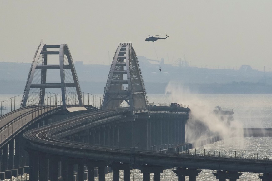 A helicopter drops water to extinguish fuel tanks ablaze on the Kerch bridge in the Kerch Strait, Crimea, October 8, 2022.  REUTERS/Stringer