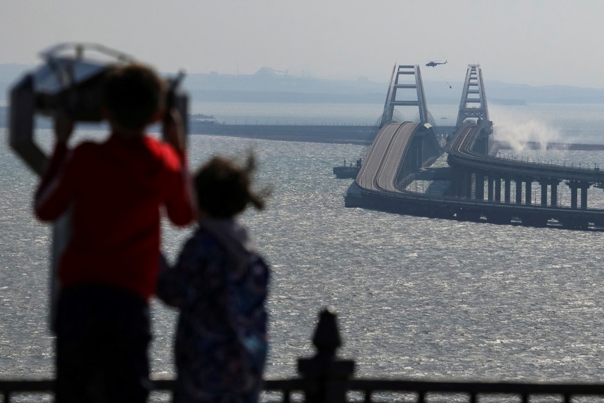 People watch fuel tanks ablaze on the Kerch bridge in the Kerch Strait, Crimea, October 8, 2022.  REUTERS/Stringer