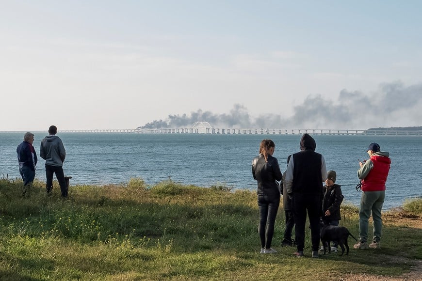 People watch fuel tanks ablaze and damaged sections of the Kerch bridge in the Kerch Strait, Crimea, October 8, 2022.  REUTERS/Stringer