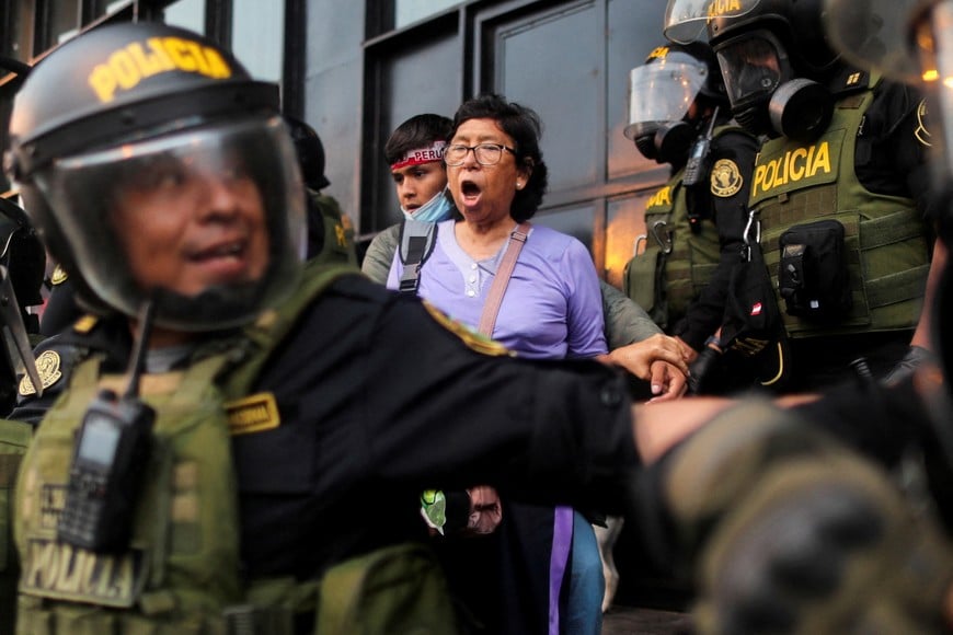 A woman surrounded by police officers takes part in a protest after the government announced a nationwide state of emergency, following a week of protests sparked by the ousting of former President Pedro Castillo, in Lima, Peru December 15, 2022. REUTERS/Sebastian Castaneda     TPX IMAGES OF THE DAY
