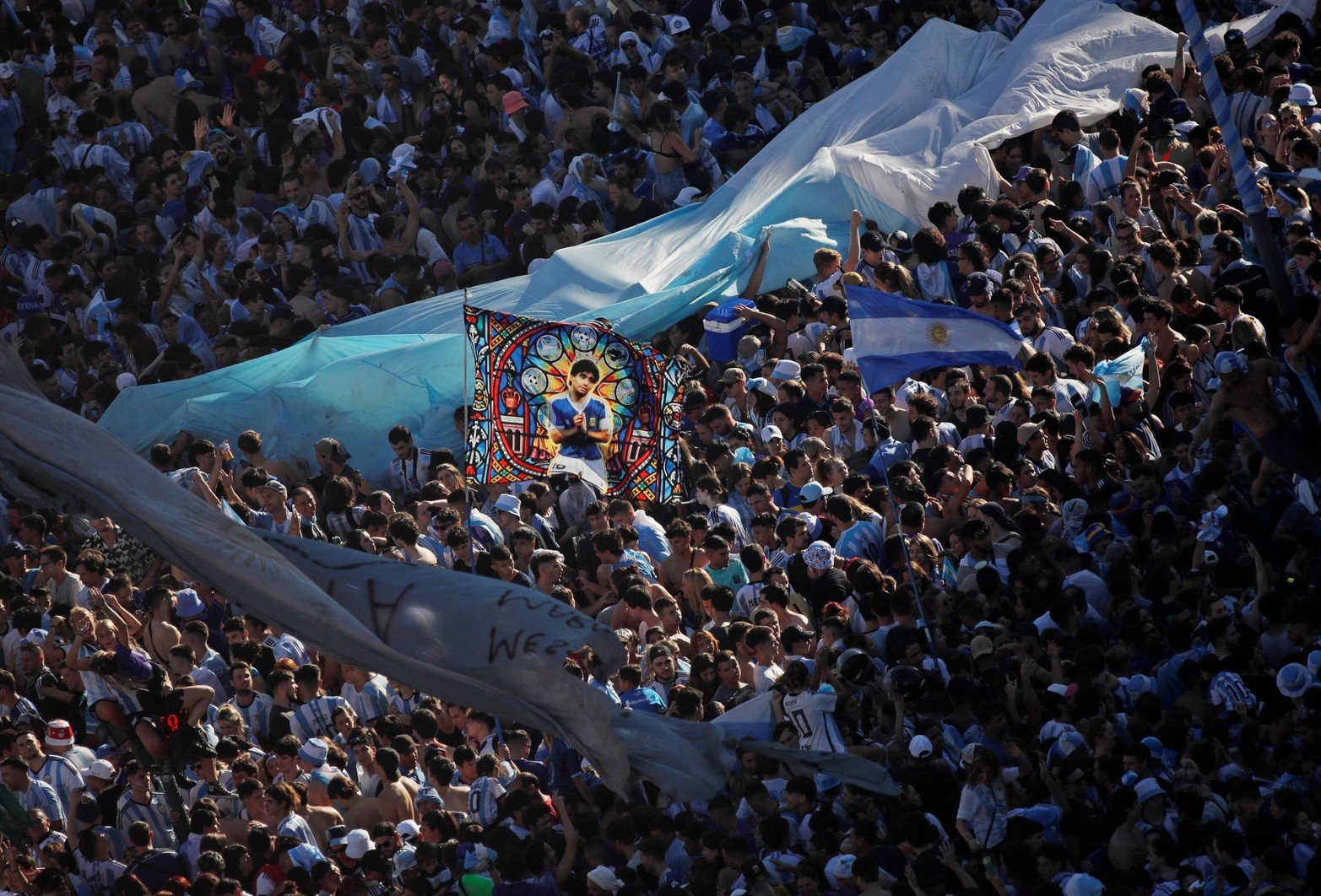 Soccer Football - FIFA World Cup Final Qatar 2022 - Fans in Buenos Aires - Buenos Aires, Argentina - December 18, 2022 
General view as Argentina fans with a Diego Maradona flag celebrate after winning the World Cup by the Obelisco REUTERS/Agustin Marcarian