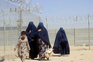 Afghan women clad in burqas and a child walk next to a fence as they cross into Pakistan via Friendship Gate crossing point in the Pakistan-Afghanistan border town of Chaman, Pakistan September 4, 2021. REUTERS/Abdul Khaliq Achakzai NO RESALES. NO ARCHIVE