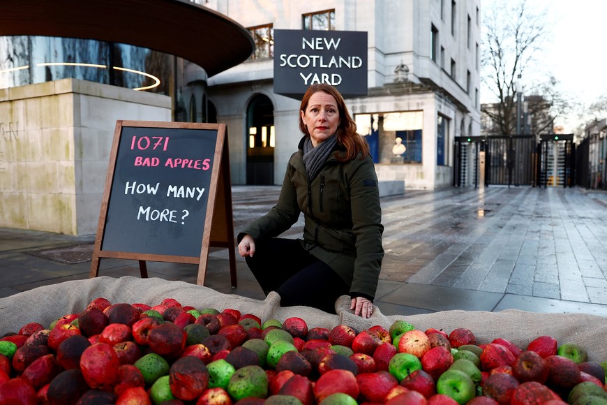CEO of Refuge, Ruth Davison poses with plastic rotten apples apples during a protest outside New Scotland Yard in London, Britain, January 20, 2023. REUTERS/Peter Nicholls
