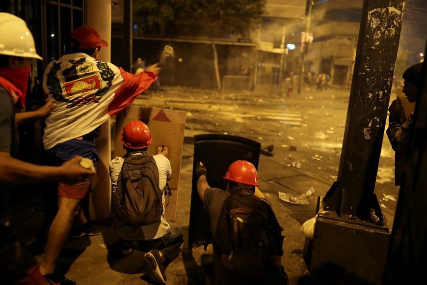 Demonstrators hurl stones while they take cover during an anti-government demonstration following the ouster of Peru's former President Pedro Castillo, in Lima, Peru January 26, 2023. REUTERS/Sebastian Castaneda