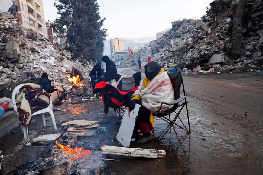A person keeps warm by a fire as the search for survivors continues in the aftermath of a deadly earthquake in Kahramanmaras, Turkey February 13, 2023. REUTERS/Suhaib Salem

     TPX IMAGES OF THE DAY