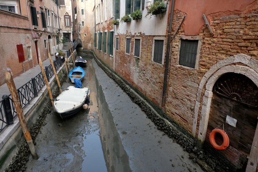 Boats are pictured in a canal during a severe low tide in the lagoon city of Venice, Italy, February 17, 2023. REUTERS/Manuel Silvestri REFILE - CORRECTING YEAR