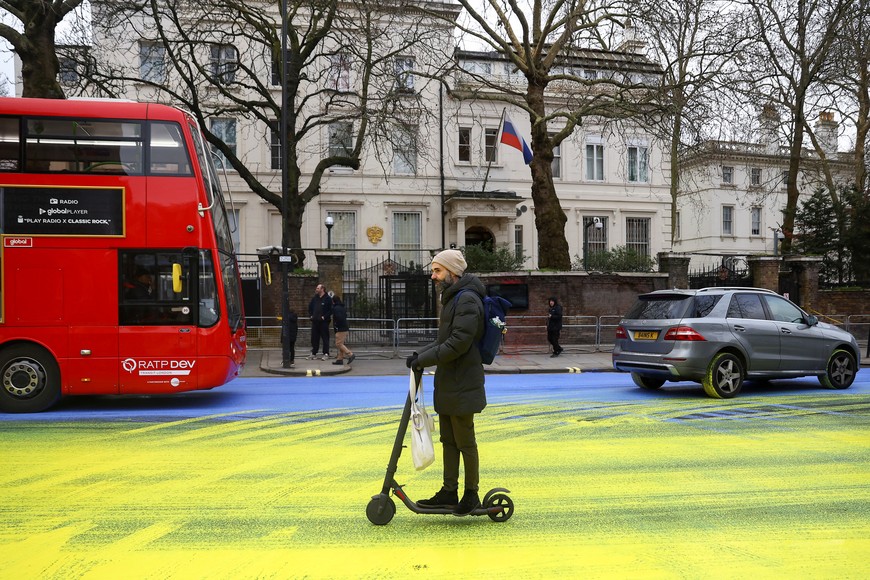 A man rides a push-scooter on a painted road, after Protest group 'Led by Donkeys' spread paint in the colours of the Ukrainian flag on the road, ahead of the first anniversary of Russia's invasion of Ukraine, outside the Russian Embassy in London, Britain February 23, 2023. REUTERS/Hannah McKay