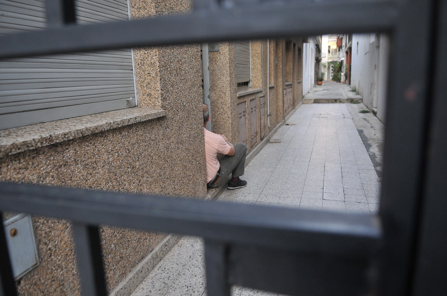 Un vecino en la puerta de su casa mira hacia ningún lugar. Ese portón seguramente lo aisló durante meses.