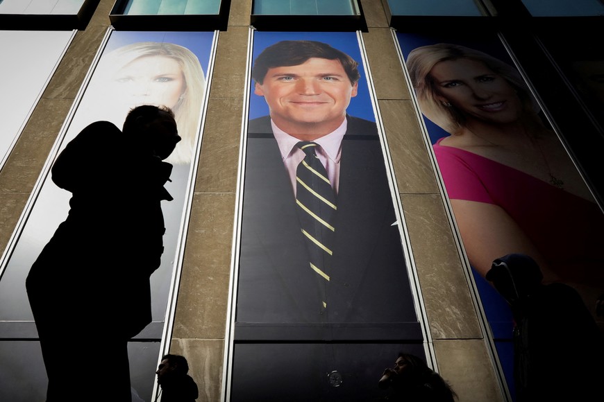 FILE PHOTO: People pass by a promo of Fox News host Tucker Carlson on the News Corporation building in New York, U.S., March 13, 2019. REUTERS/Brendan McDermid/ File Photo
