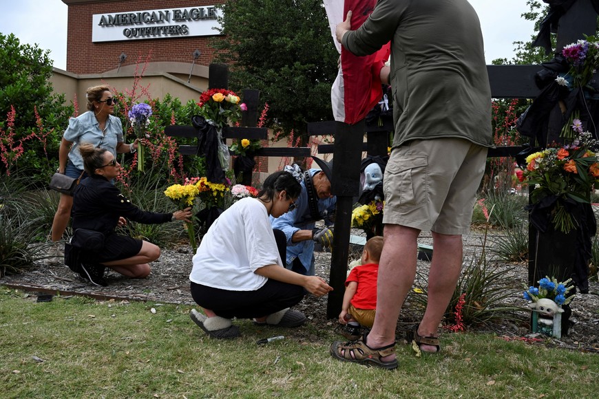 Mahboubeh Gargvand and Sara Tabatabaei place flowers as Lenna Maleki helps muralist Roberto Marquez, from Dallas, erect a memorial to honor those who lost their lives on Saturday when a gunman shot multiple people at the Dallas-area Allen Premium Outlets mall, in Allen, Texas, U.S. May 7, 2023. Robert says, "This is like a refuge for the people who lost loved ones, a place where they can come and express all their emotions”. He believes that the memorial is a priority for the difficult situation, and that people need a place to gather. REUTERS/Jeremy Lock