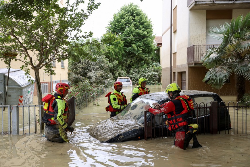 Firefighters work next to a flooded car, after heavy rains hit Italy's Emilia Romagna region, in Faenza, Italy, May 18, 2023. REUTERS/Claudia Greco