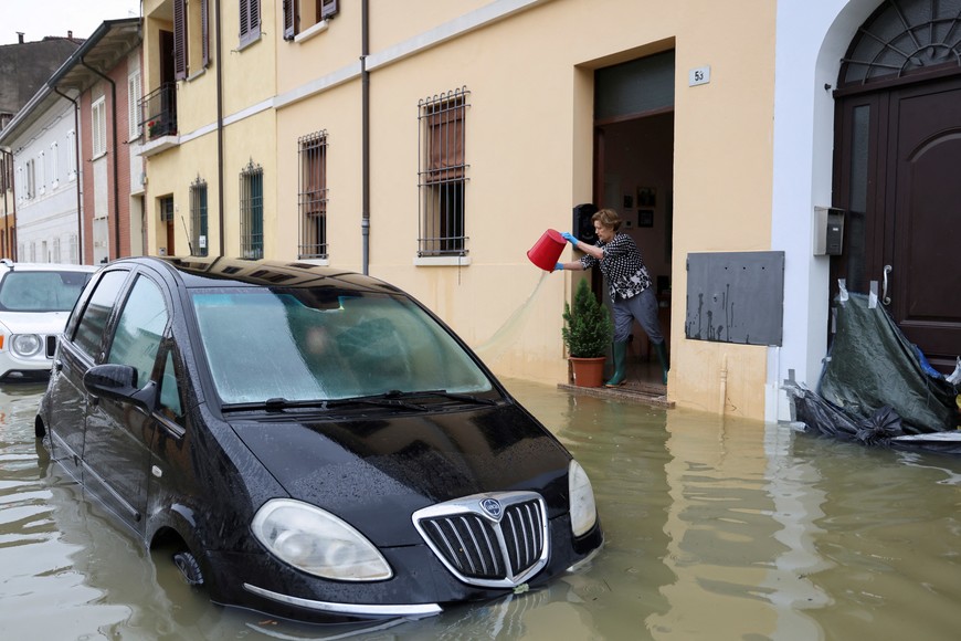 A resident pours water out from a building after heavy rains hit Italy's Emilia Romagna region, in Lugo, Italy, May 19, 2023. REUTERS/Claudia Greco