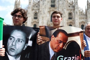 People hold pictures of the former Italian Prime Minister Silvio Berlusconi, on the day of his funeral, in Milan, Italy June 14, 2023. REUTERS/Guglielmo Mangiapane