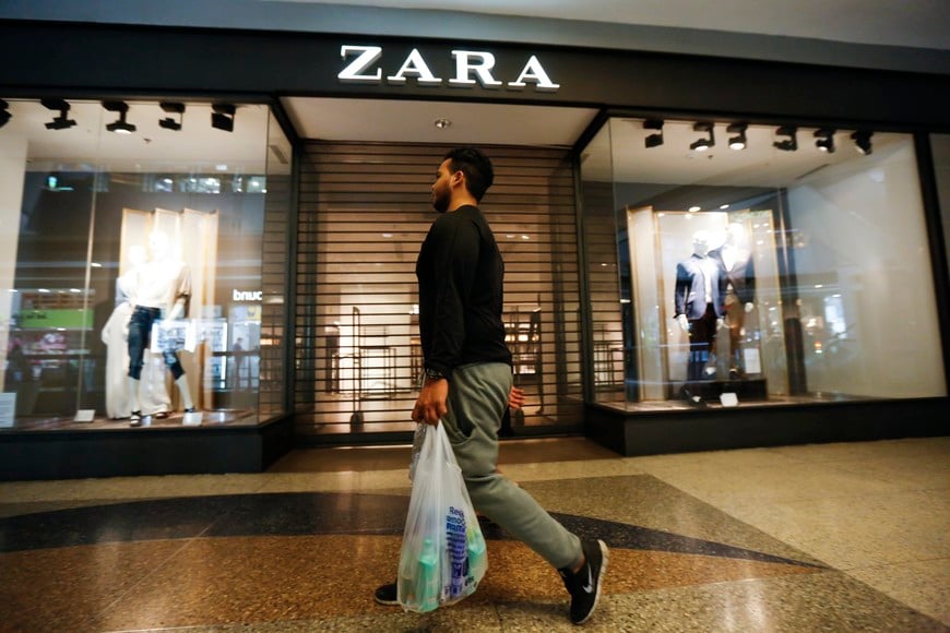 A man walks past a Zara retail store, with its shutters drawn, at a mall in Caracas September 30, 2014. REUTERS/Carlos Garcia Rawlins (VENEZUELA - Tags: BUSINESS) venezuela caracas  venezuela crisis economica recesion comercios negocios ropa moda zara