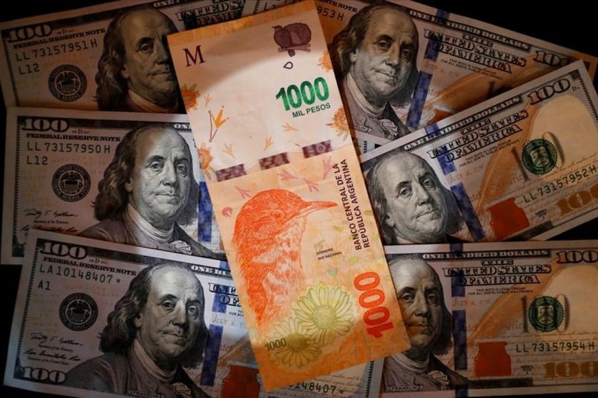 FOTO DE ARCHIVO-Un billete de mil pesos argentinos sobre varios billetes de cien dólares estadounidenses. Oct 17, 2022. REUTERS/Agustin Marcarian