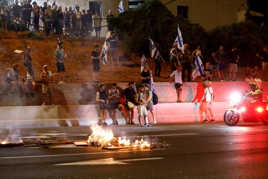 Protesters stand near a burning fire as they block part of Ayalon Highway during a demonstration following a parliament vote on a contested bill that limits Supreme Court powers to void some government decisions, in Tel Aviv, Israel July 24, 2023. REUTERS/Corinna Kern