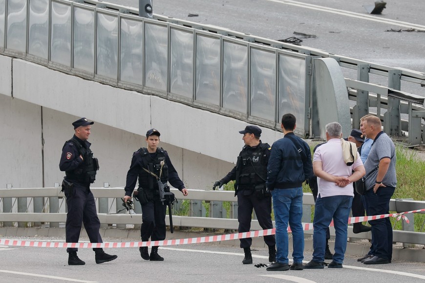 A police officer carries debris to the members of the security services investigating a bridge near the site of a damaged building following a reported drone attack in Moscow, Russia, July 24, 2023. REUTERS/Maxim Shemetov