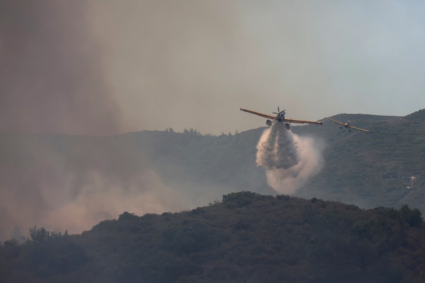 Firefighting planes make water drops as a wildfire burns near the village of Vati, on the island of Rhodes, Greece, July 25, 2023. REUTERS/Nicolas Economou