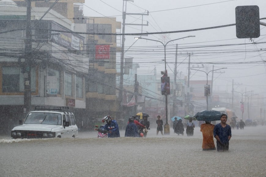 People wade through a flooded road caused by monsoon rains and the recent typhoon Doksuri, in Balagtas, Bulacan province, Philippines, July 29, 2023. REUTERS/Lisa Marie David