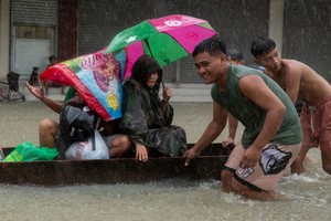 People ride on a makeshift boat at a flooded road caused by monsoon rains and the recent typhoon Doksuri, in Balagtas, Bulacan province, Philippines, July 29, 2023. REUTERS/Lisa Marie David