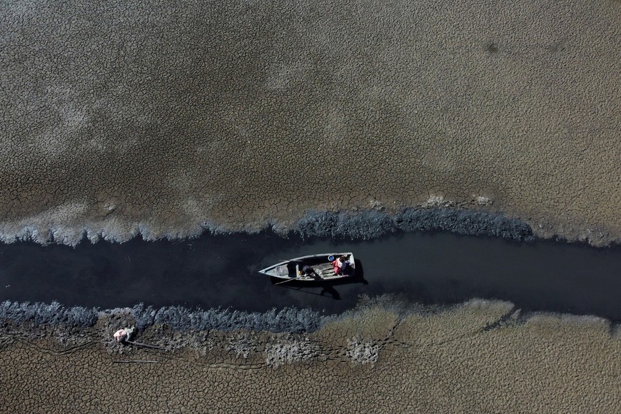 Isabel Apaza and Gabriel Flores sail in their boat through a narrow water path near the shore of Lake Titicaca in drought season in Huarina, Bolivia August 3, 2023. REUTERS/Claudia Morales