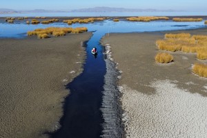 Isabel Apaza and Gabriel Flores sail in their boat through a narrow water path near the shore of Lake Titicaca in drought season in Huarina, Bolivia August 3, 2023. REUTERS/Claudia Morales     TPX IMAGES OF THE DAY
