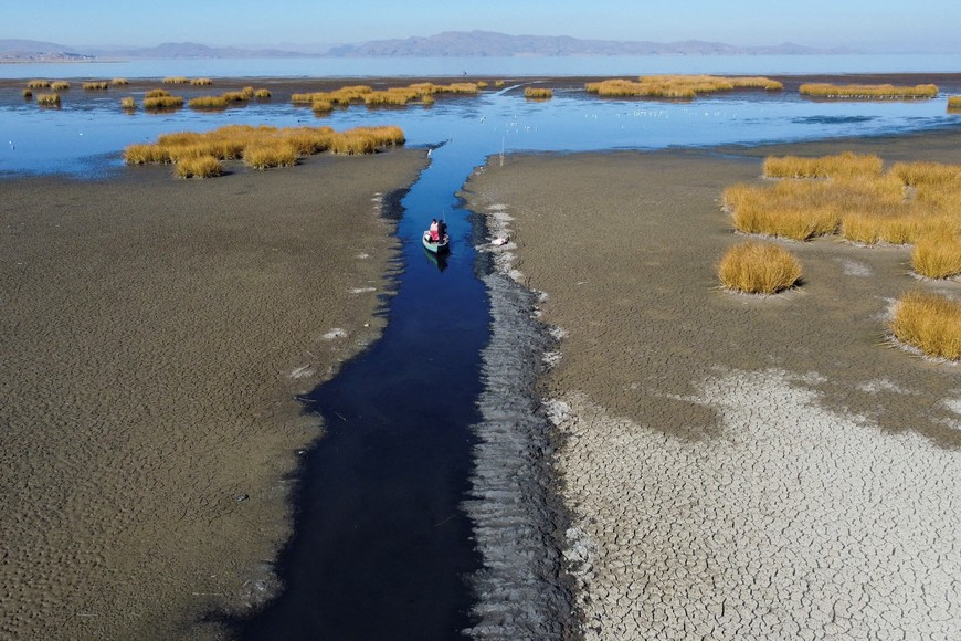 Isabel Apaza and Gabriel Flores sail in their boat through a narrow water path near the shore of Lake Titicaca in drought season in Huarina, Bolivia August 3, 2023. REUTERS/Claudia Morales     TPX IMAGES OF THE DAY