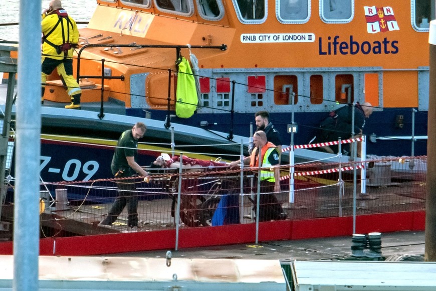 Rescue personnel assist a migrant who was brought ashore, after a boat carrying migrants from France sunk in the English Channel, in Dover, Britain August 12, 2023, in this still image obtained from social media. Stuart Brock/via REUTERS  THIS IMAGE HAS BEEN SUPPLIED BY A THIRD PARTY. MANDATORY CREDIT.