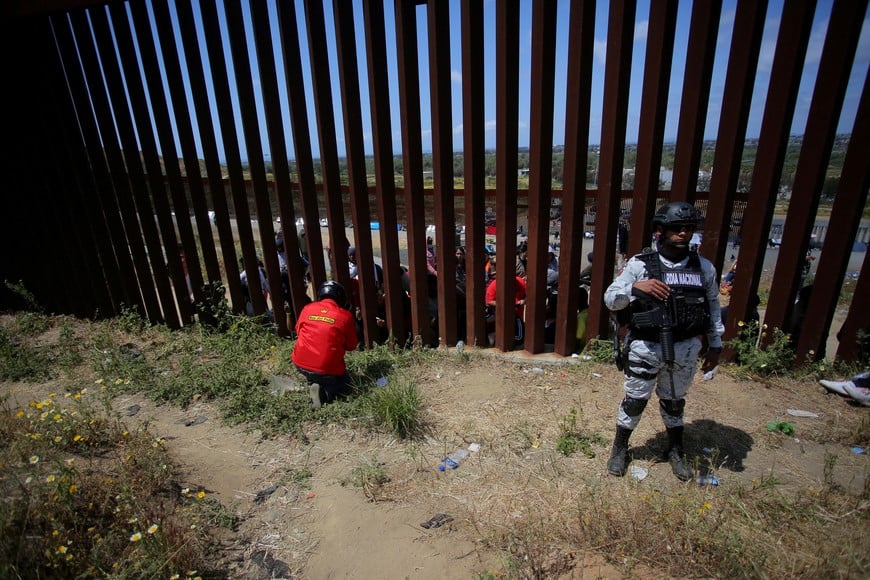 FILE PHOTO: A member of the National Guard keeps watch as a food delivery employee takes orders from migrants standing between the primary and secondary fences, as the United States prepares to lift COVID-19 era restrictions known as Title 42, that have blocked migrants at the U.S.- Mexico border from seeking asylum since 2020, as seen from Tijuana, Mexico May 10, 2023. REUTERS/Jorge Duenes/File Photo