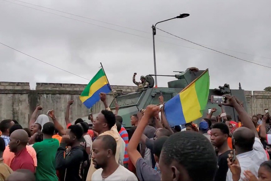 A military vehicle passes by people celebrating after military officers announced they had taken power, after the state election body announced President Ali Bongo had won a third term, in Port Gentil, Gabon August 30, 2023 in this still image obtained from social media video. Gaetan M-Antchouwet via REUTERS  THIS IMAGE HAS BEEN SUPPLIED BY A THIRD PARTY. MANDATORY CREDIT. NO RESALES. NO ARCHIVES.