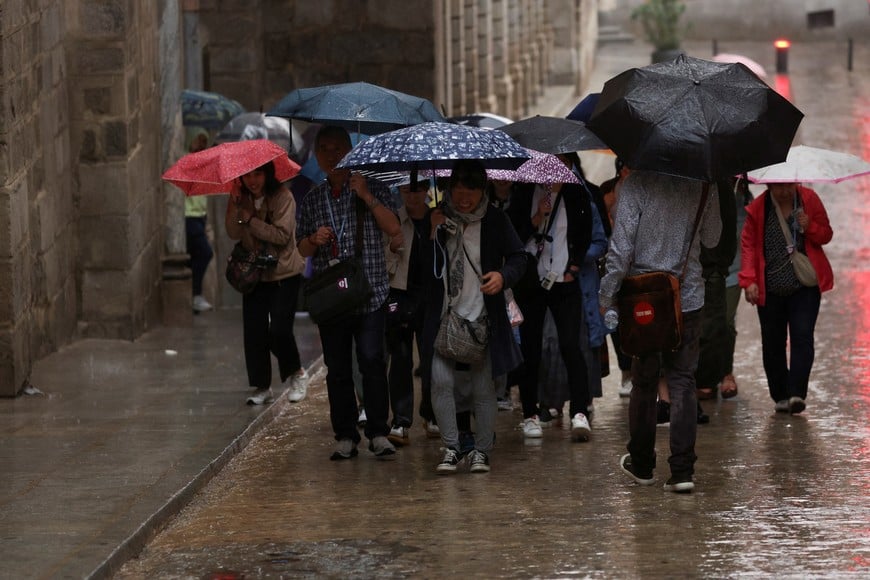 A group of tourists take shelter under umbrellas from heavy rain as they tour in Toledo, Spain September 3, 2023. REUTERS/Isabel Infantes