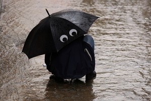 A woman takes shelter under an umbrella from heavy rain as she tours in Toledo, Spain September 3, 2023. REUTERS/Isabel Infantes