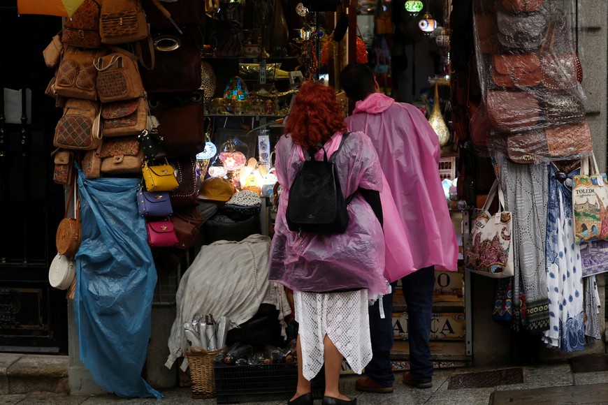 A couple of tourists wearing rain ponchos as they tour in Toledo, Spain September 3, 2023. REUTERS/Isabel Infantes