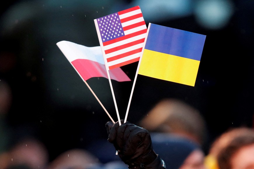 A man holds Ukrainian, Polish and U.S. flags before U.S. President Joe Biden addresses the public during an event outside the Royal Castle, in Warsaw, Poland, February 21, 2023. REUTERS/David W Cerny     TPX IMAGES OF THE DAY