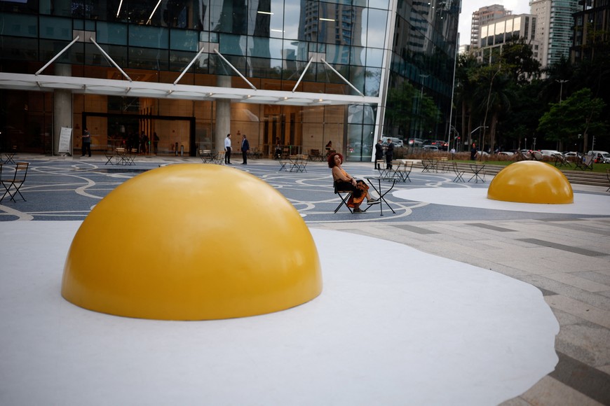 A woman sits near the "Art Eggcident" installation by Dutch artist Henk Hofstra at Faria Lima Avenue, in Sao Paulo, Brazil, September 18, 2023. REUTERS/Amanda Perobelli