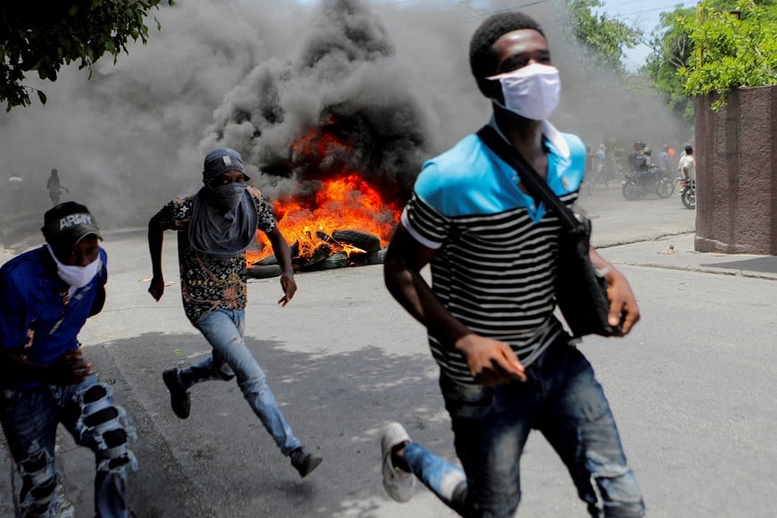 Men run next to burning tires during a protest demanding an end to gang violence, in Port-au-Prince, Haiti, August 14, 2023. REUTERS/Ralph Tedy Erol     TPX IMAGES OF THE DAY