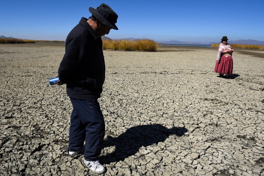 FILE PHOTO: Gabriel Flores and Isabel Apaza walk on the dry, cracked bed near the shore of Lake Titicaca in drought season in Huarina, Bolivia August 3, 2023. REUTERS/Claudia Morales/File Photo