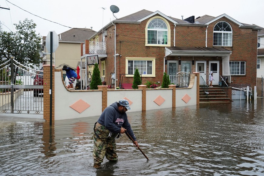 A resident surnamed Mahamad, a driving instructor and bus driver, attempts to unclog leaves and other debris from drainage holes in the flooded street of Rau Court, as the remnants of Tropical Storm Ophelia bring flooding across the mid-Atlantic and Northeast, in the Hamilton Beach neighborhood in the Queens borough of New York City, U.S., September 29, 2023.  REUTERS/Bing Guan