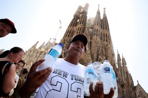 A man sells bottles of water for tourists waiting for entrance in the Sagrada Familia basilica in Barcelona, while Europe is on red alert as heatwave brings health warning, Spain July 18, 2023. REUTERS/Nacho Doce