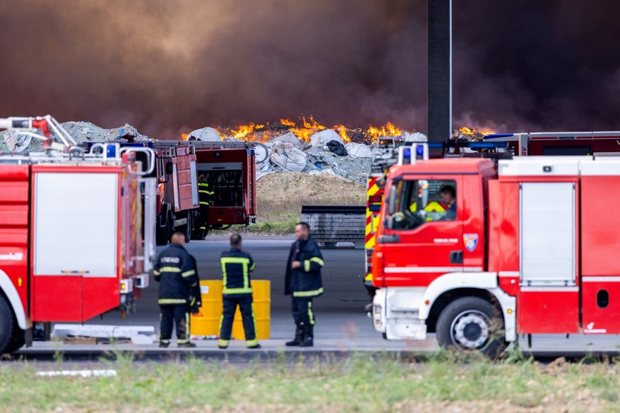 Firefighters stand near the fire at Drava International factory near Osijek, Croatia, October 4, 2023. REUTERS/Antonio Bronic