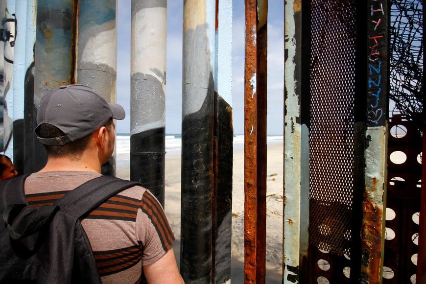 Mexican migrant Eberardo, who survived the shipwreck of a 40-foot cabin cruiser carrying 32 migrants from Mexico to San Diego in May, stands in front of the border wall at Playas Tijuana, in Tijuana, Mexico July 11, 2021. Picture taken July 11, 2021. REUTERS/Jorge Duenes