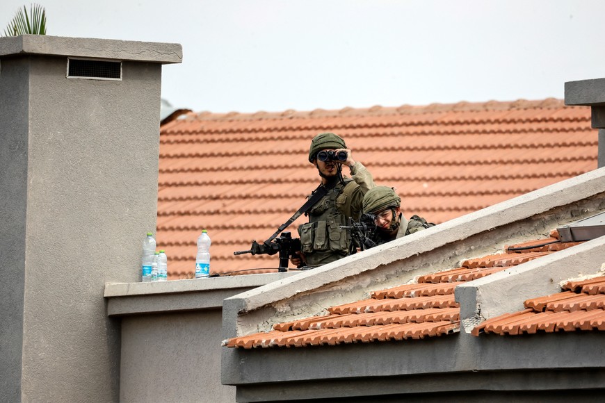 Israeli soldiers look out as they stand between buildings, as violence around the nearby Gaza Strip mounts following a mass-rampage by armed Palestinian infiltrators, in Sderot, southern Israel, October 9, 2023. REUTERS/Amir Cohen