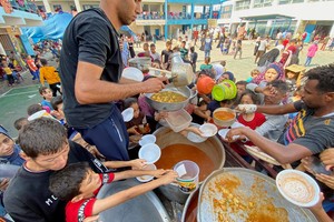 FILE PHOTO: Palestinians, who fled their houses due to Israeli strikes, gather to get their share of charity food offered by volunteers, amid food shortages, at a UN-run school where they take refuge, in Rafah, in the southern Gaza Strip, October 23, 2023. REUTERS/Mahmoud al-Masri/File Photo